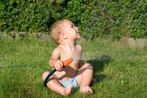 Kleinkind spielt mit Rasensprenger